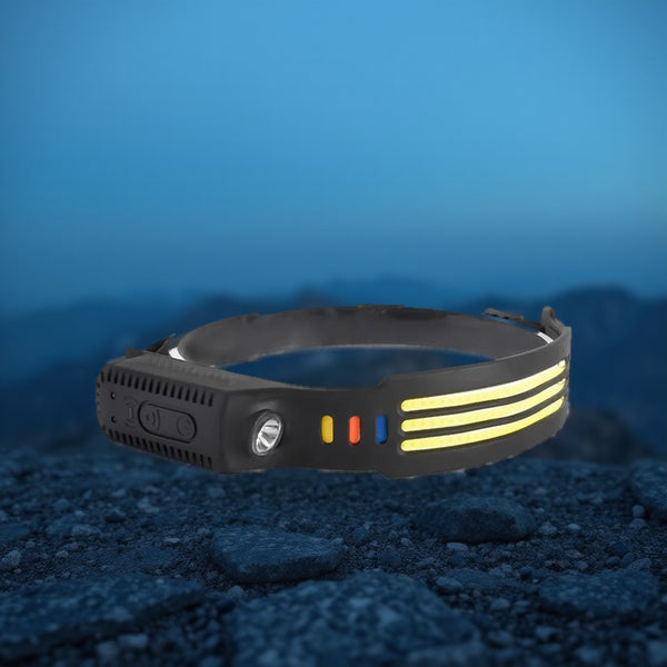 Three-strip LED headlamp resting on dark rock at dusk, mountain ridgeline behind