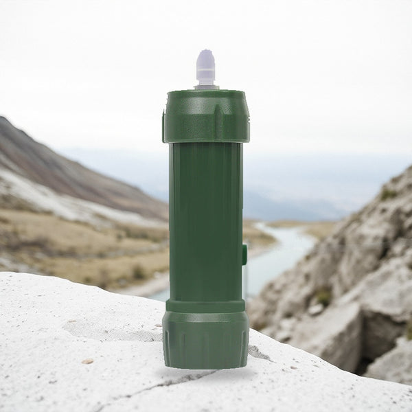 Green stream water filter standing on a pale granite ledge above a mountain valley