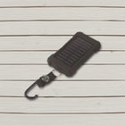Black solar power bank with compass strap and carabiner lying on pale wooden boards