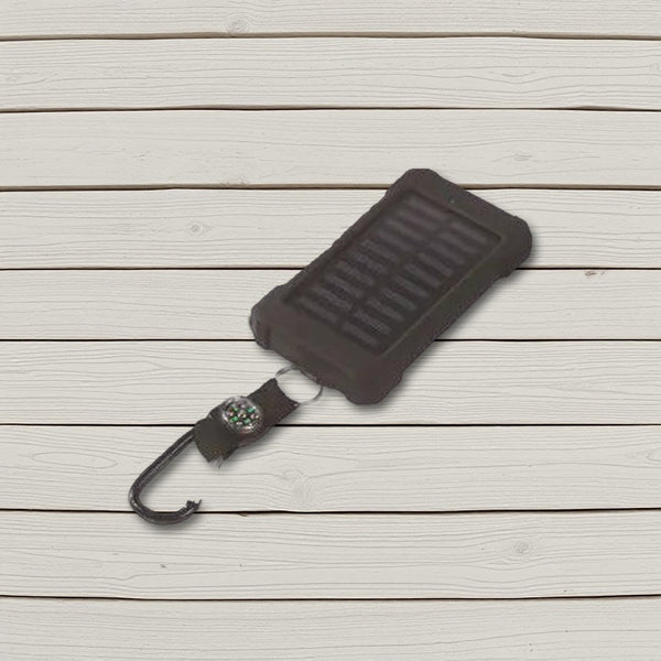 Black solar power bank with compass strap and carabiner lying on pale wooden boards