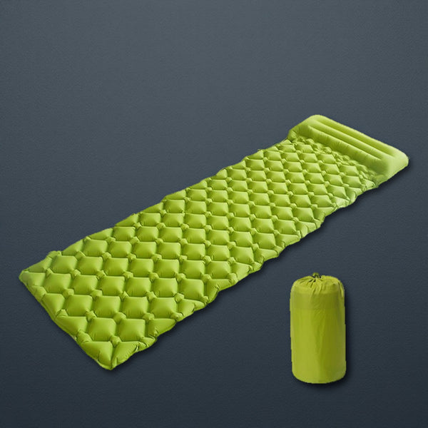 Lime green inflatable sleeping pad with built-in pillow and stuff sack on dark slate
