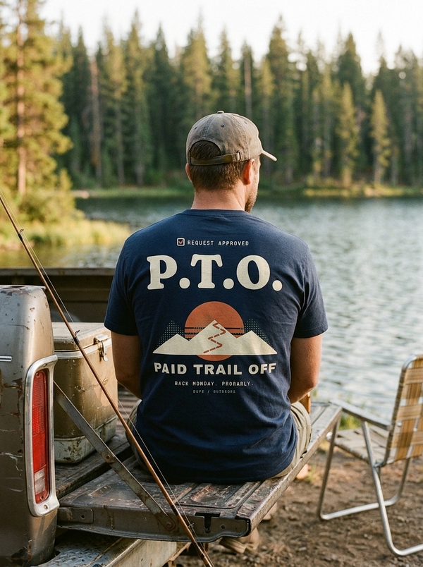 Man in a navy P.T.O. tee on a pickup tailgate by a lake